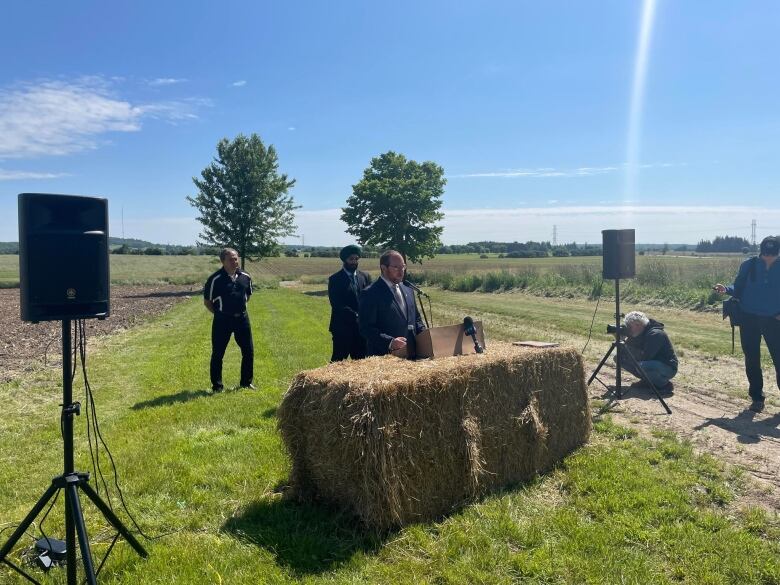 a man speaking at a hay bale podium 