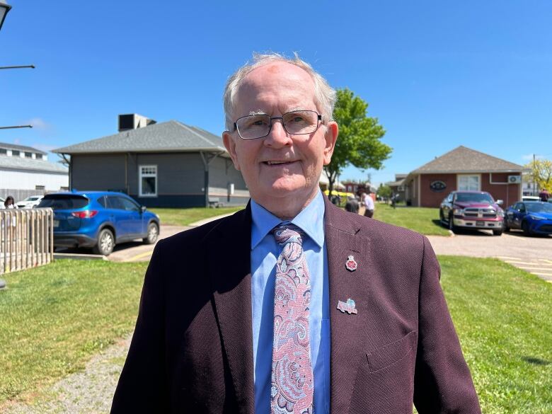 A man in formal clothing smiles at the camera.