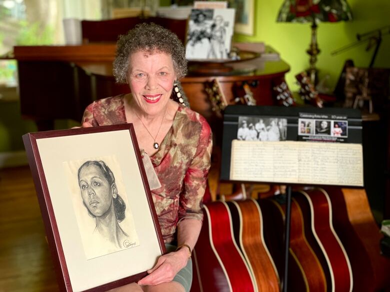 A woman sitting on a couch holds a framed portrait.