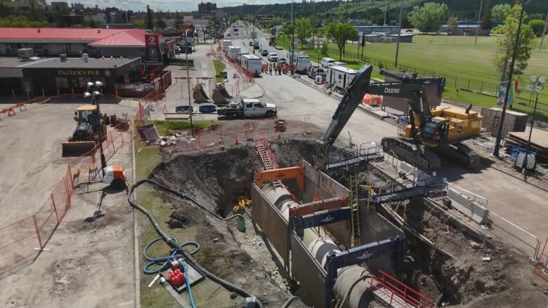 roads are closed and a giant hole is in the ground as heavy duty machinery work.