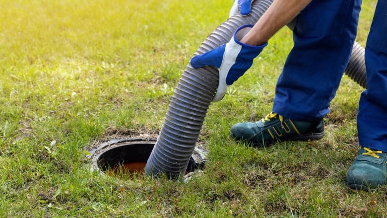 man pumping out house septic tank. drain and sewage cleaning service.