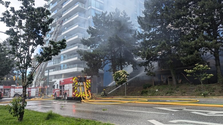 Fire trucks and firefighters are seen spewing water at a small building.