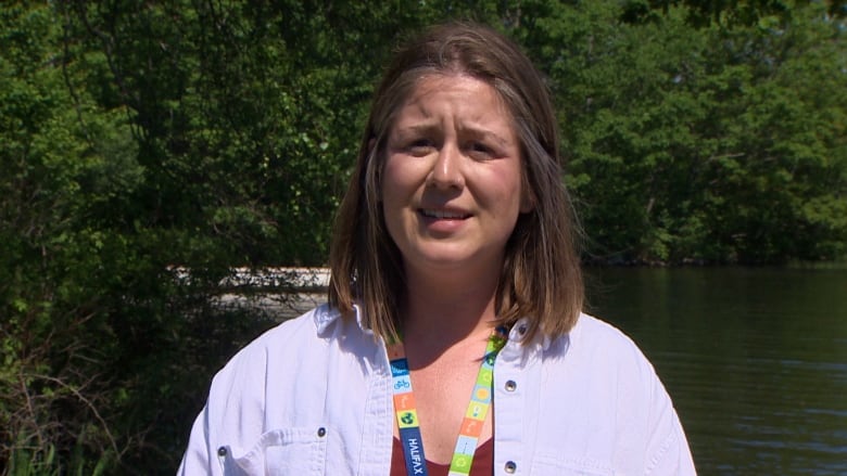 A woman with brown hair who is wearing a blue shirt looks at the camera.