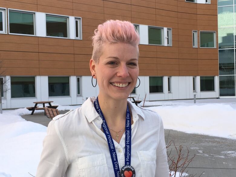 A portrait of a woman smiling outside a building.