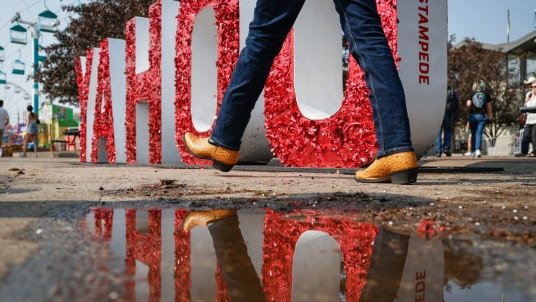 cowboy boots reflected in a puddle, with a large YAHOO sign in the background.