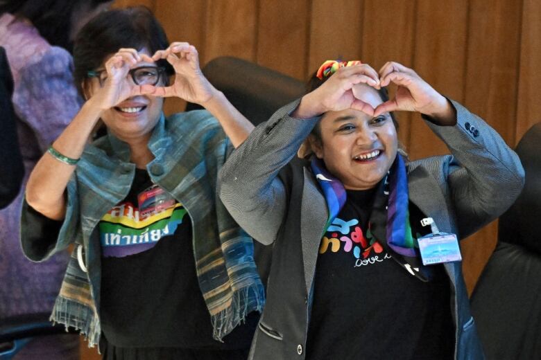 Two activists make heart shapes with their fingers following the passage of a marriage equality bill in the Thai parliament.