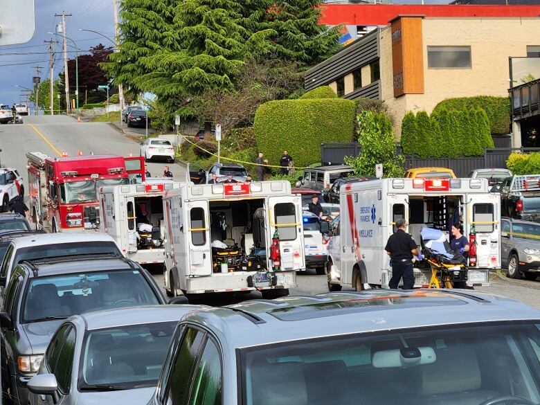 A close-up of 3 ambulances and a fire truck on a road.