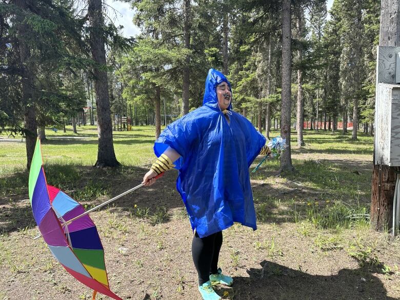 A person in a bright blue raincoat holds out a brightly coloured umbrella.