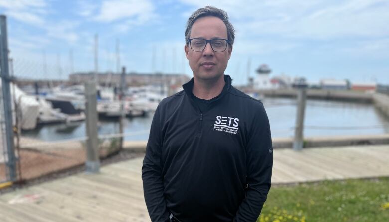 A man stands in front of a marina.