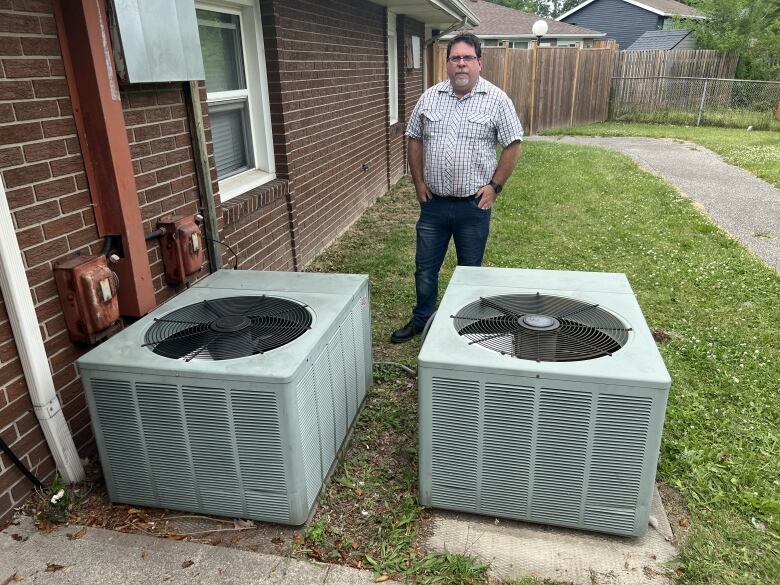 A man stands with two broken AC units