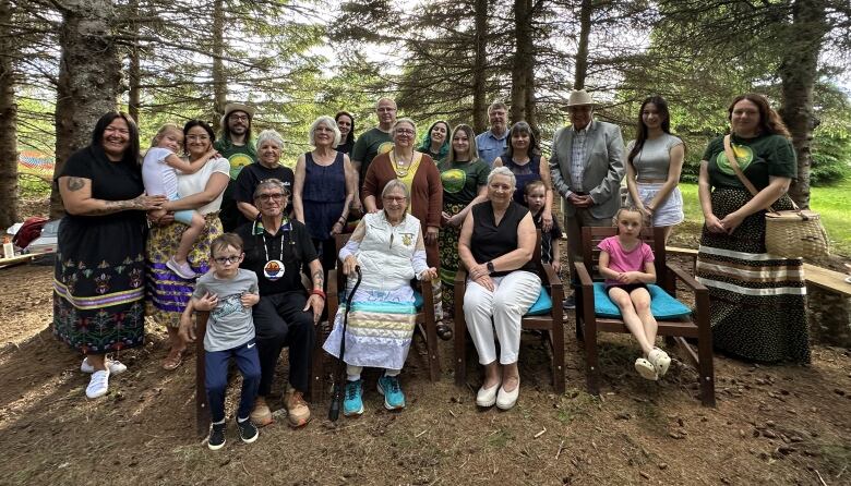 People gather for a group photo in a forest clearing.