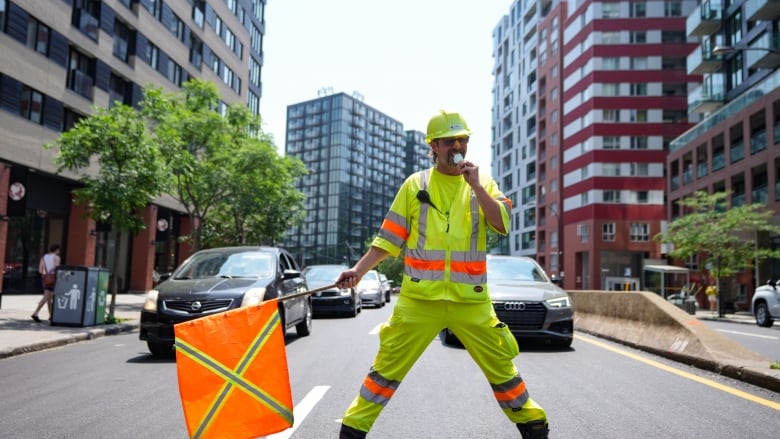 A construction worker eats a popsicle to keep cool on the worksite.