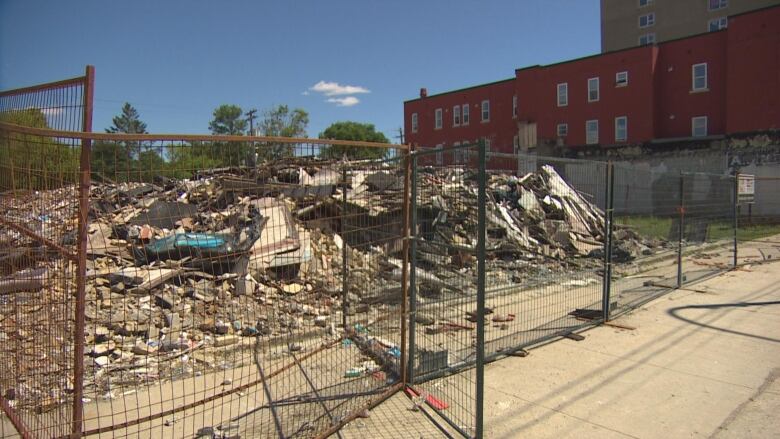 A pile of rubble is surrounded by a metal fence.