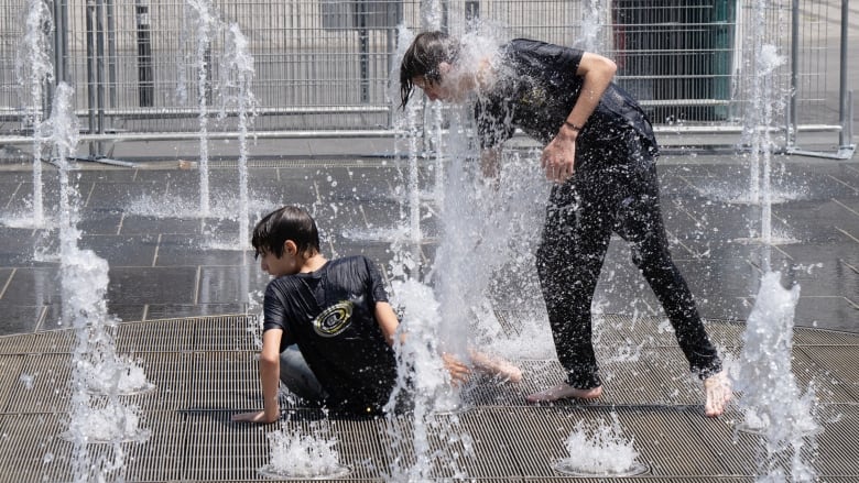 Two young people play in a splash pad