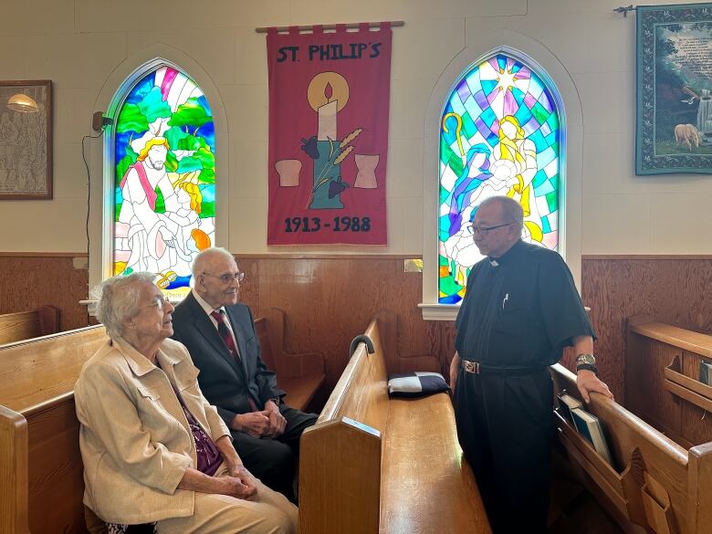 Three people talk in a church.