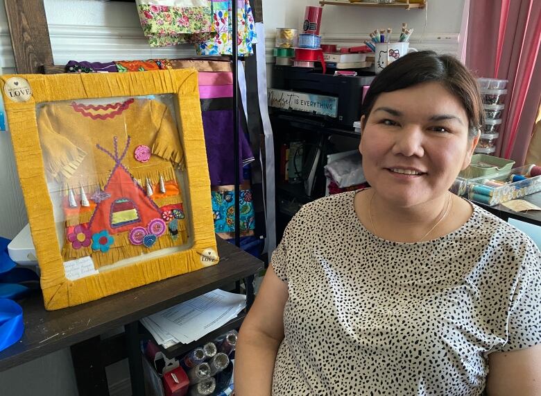 A woman sits next to an art project.