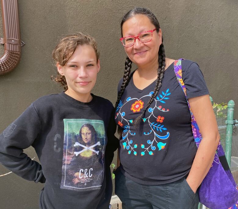 A young woman stands beside an older woman with braids.