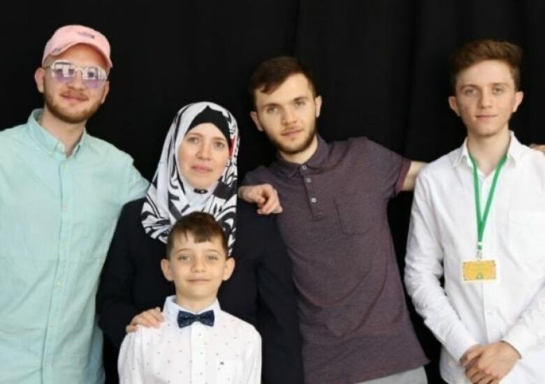 Three men, a woman and a child posing for a picture.