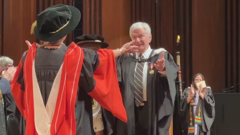 Ken Clark is congratulated by family friend Mary Bluechardt on stage at his convocation.