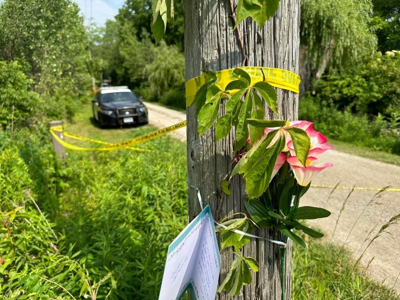 A pink and white flower on a pole next to a card with 