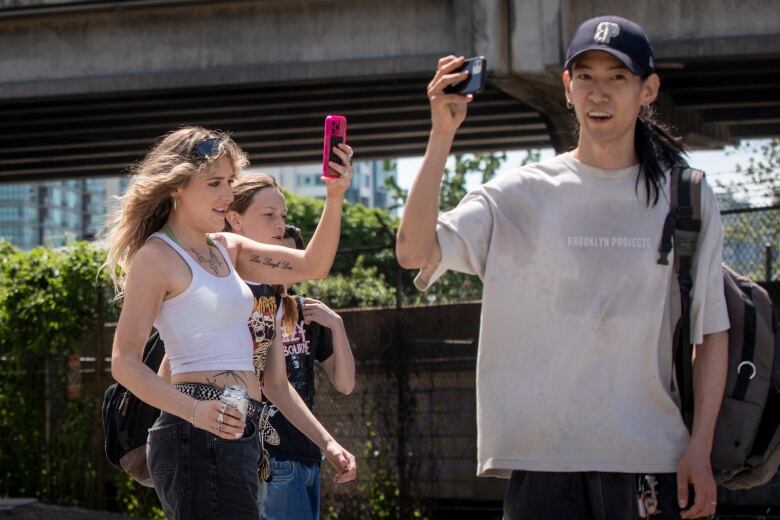 A woman and a man hold their cellphones while shooting a video.