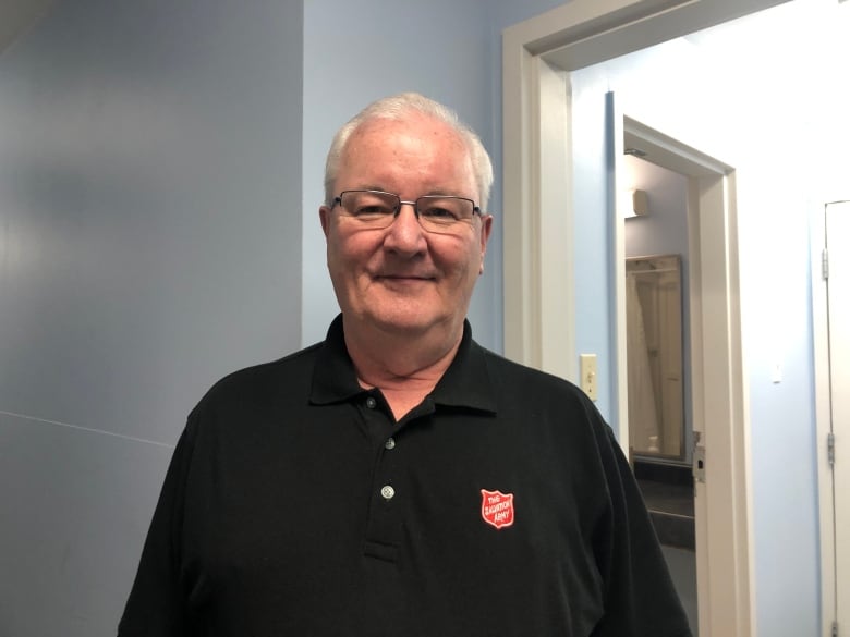 Man with a shirt that says salvation army smiles in grey room