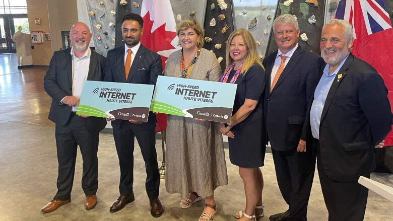 Six people posing for a photo. Some are holding signs that say high-speed internet.