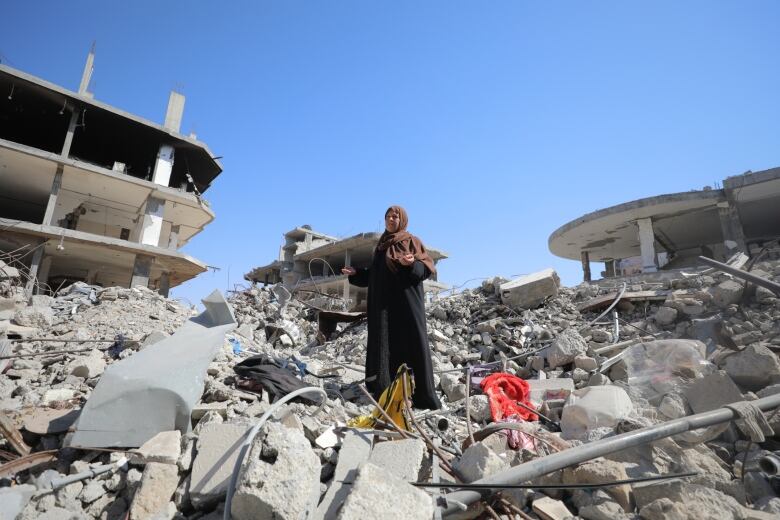 A woman stands on concrete rubble of a home.