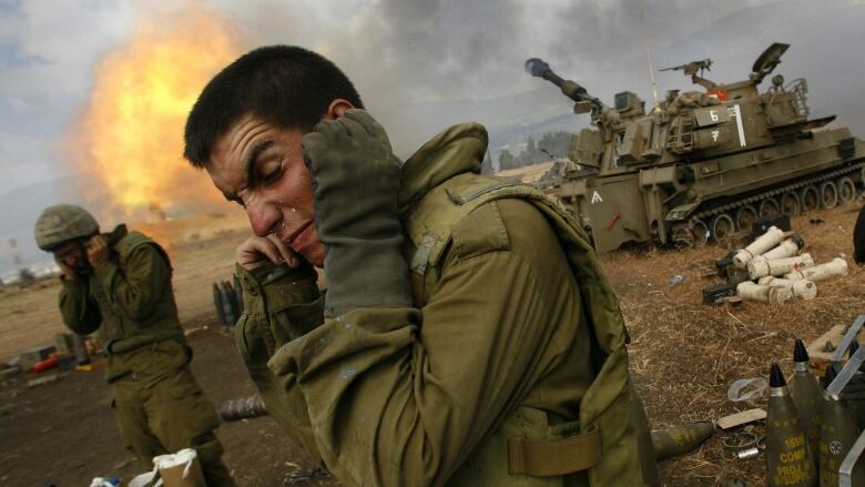 Israeli soldiers cover their ears as an artillery unit fires shells towards southern Lebanon from a position near Kiryat Shmona in northern Israel, near the border with Lebanon, on Friday, July 21, 2006. In the last 24 hours, at least six Israeli troops have been killed in pitched battles with Hezbollah militants and an Israeli helicopter pilot was killed when two Apache attack helicopters collided.