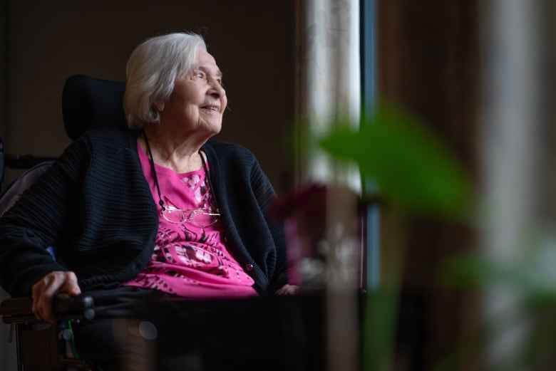 Margaret Friend looks out the window of Macassa Lodge in Hamilton, Ont. She is an older white woman wearing a pink shirt.