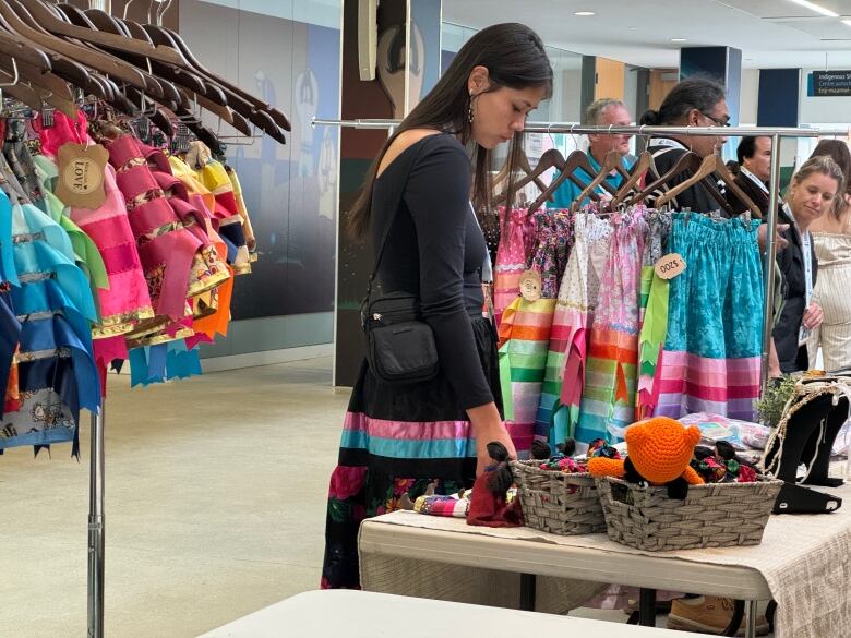 A woman looks at the items on a vendor's table