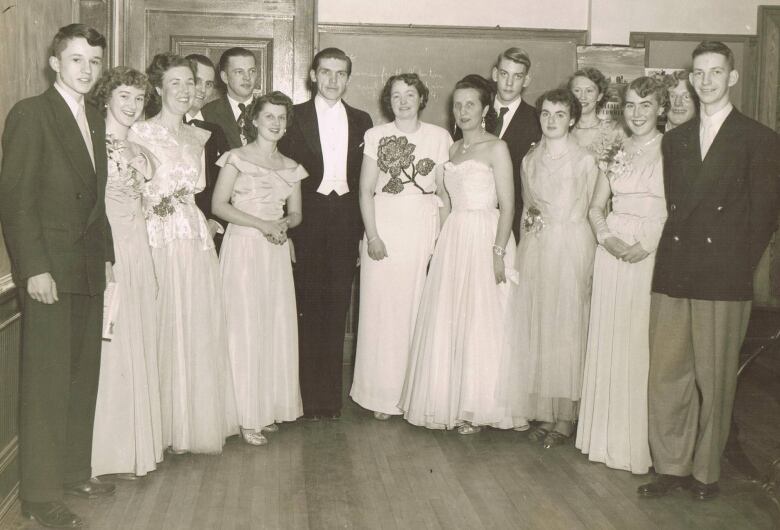 A black and white shows 15 high school students dressed in formal wear, likely at a February 1951 school dance.