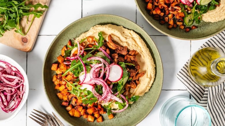 Chicken Shawarma Bowl with hummus, potatoes and a salad on top.