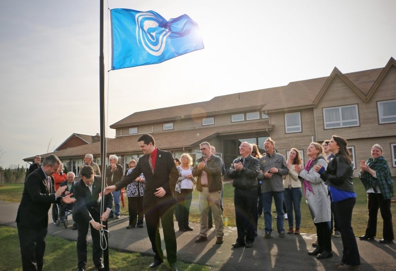 A group of people attend a flag raising outside the Gaelic college. 