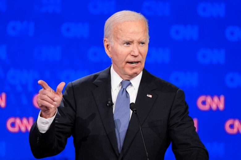 A person gestures while speaking into a microphone.