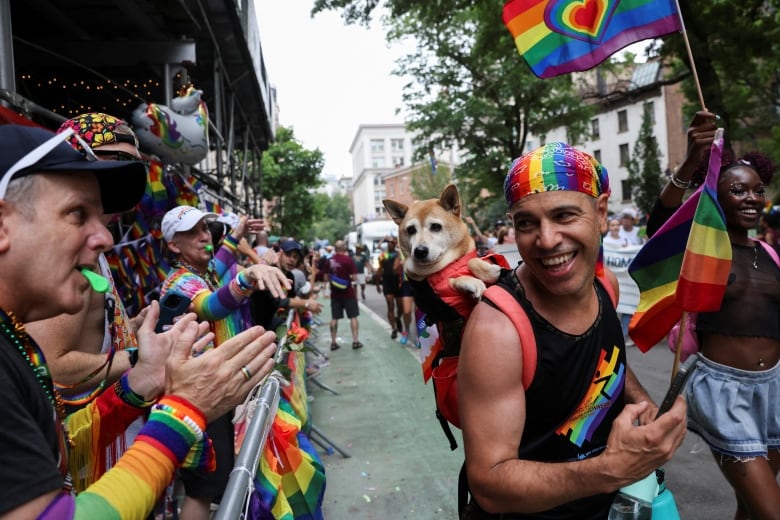 A person carries a dog on the back during a Pride march.