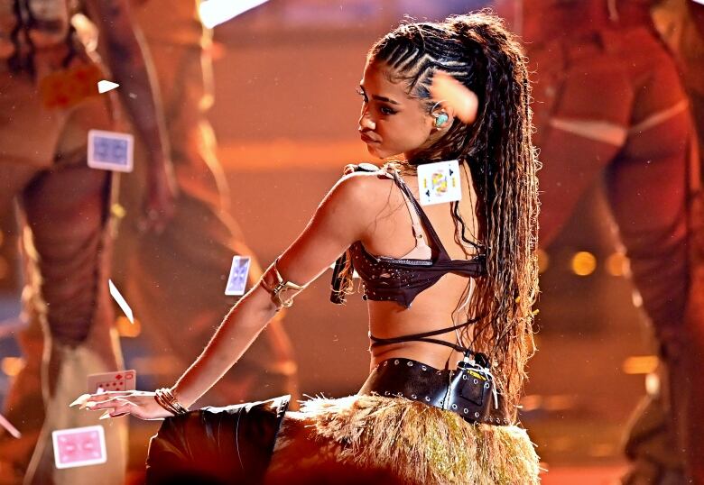 A woman performs on stage as playing cards fall around her.