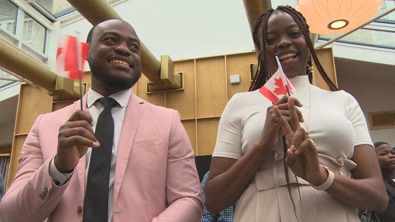 A man and woman hold Canadian flags up and smile.