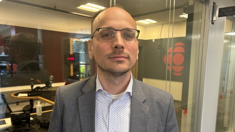 Man with grey blazer standing outside CBC radio booth.