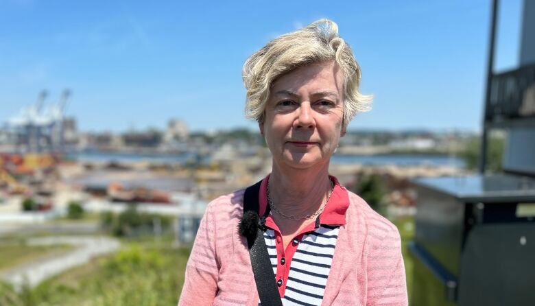 Medium shot of woman standing on grass, port in the background