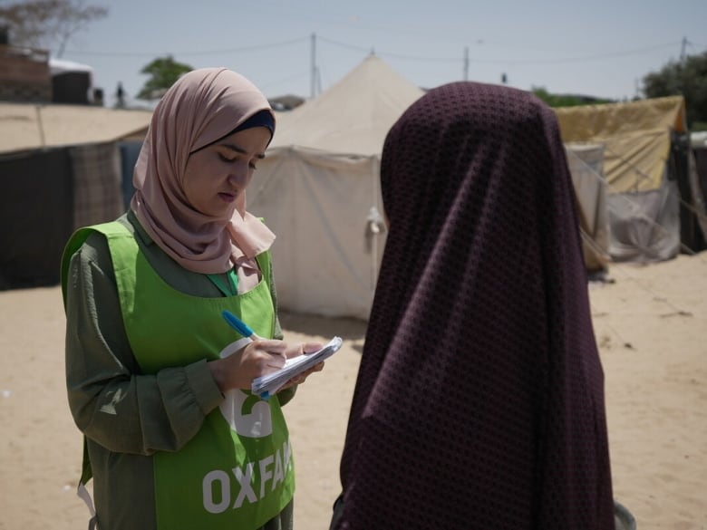 Two women with headscarfs standing outside near tents.