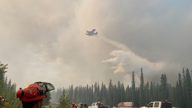 Firefighters look at smoke and water falling.