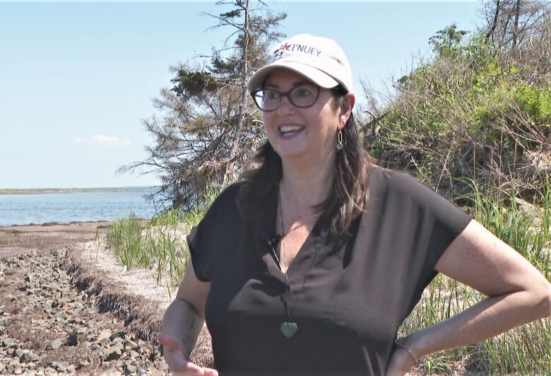 Tracey Cutcliffe stands, smiling, on a rocky beach.