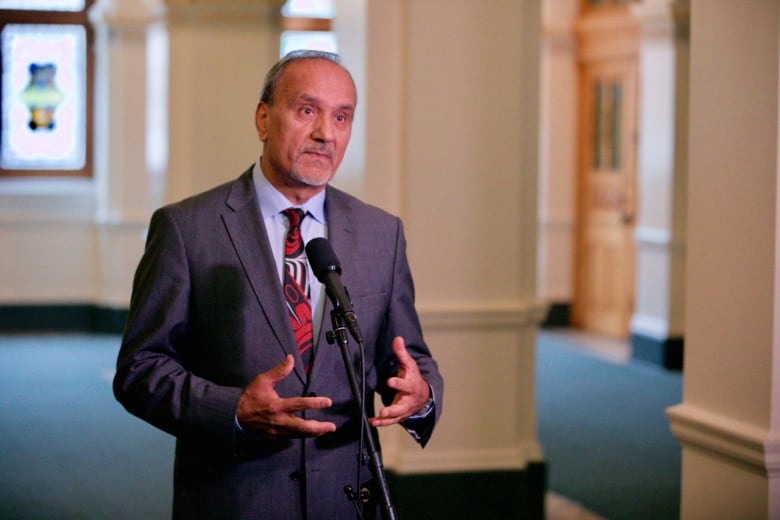 A man in a suit stands at a microphone. 