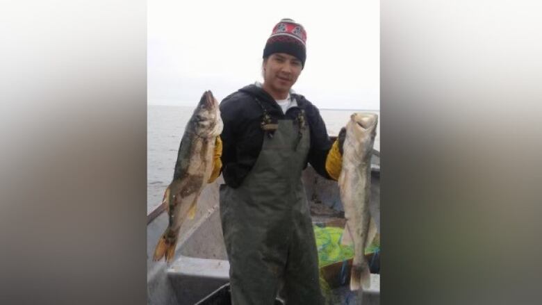 A man holding up two fish. 