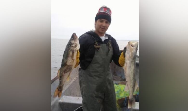 A man holding up two fish. 