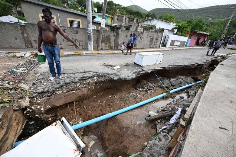 A large gap is visible in a road, with a pipe running through it.