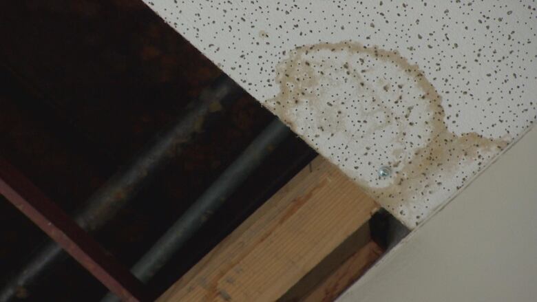 A stain is seen on a ceiling tile, while the above are exposed.