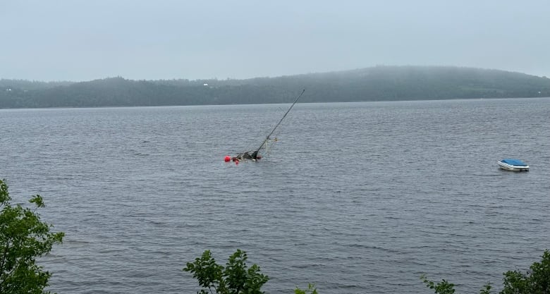 Partially submerged sailboat as seen from shore. 