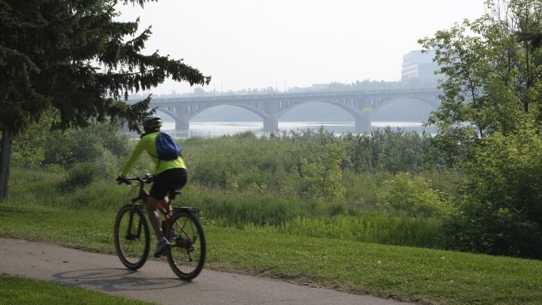 a person is biking by and there is a bridge and water behind them